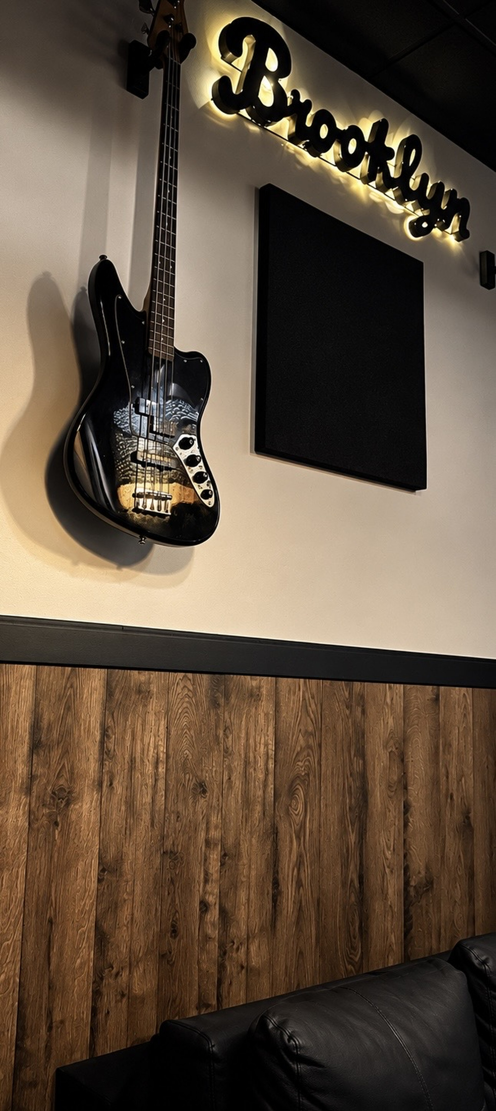 Illuminated Brooklyn sign and bass guitar above the studio’s seating area